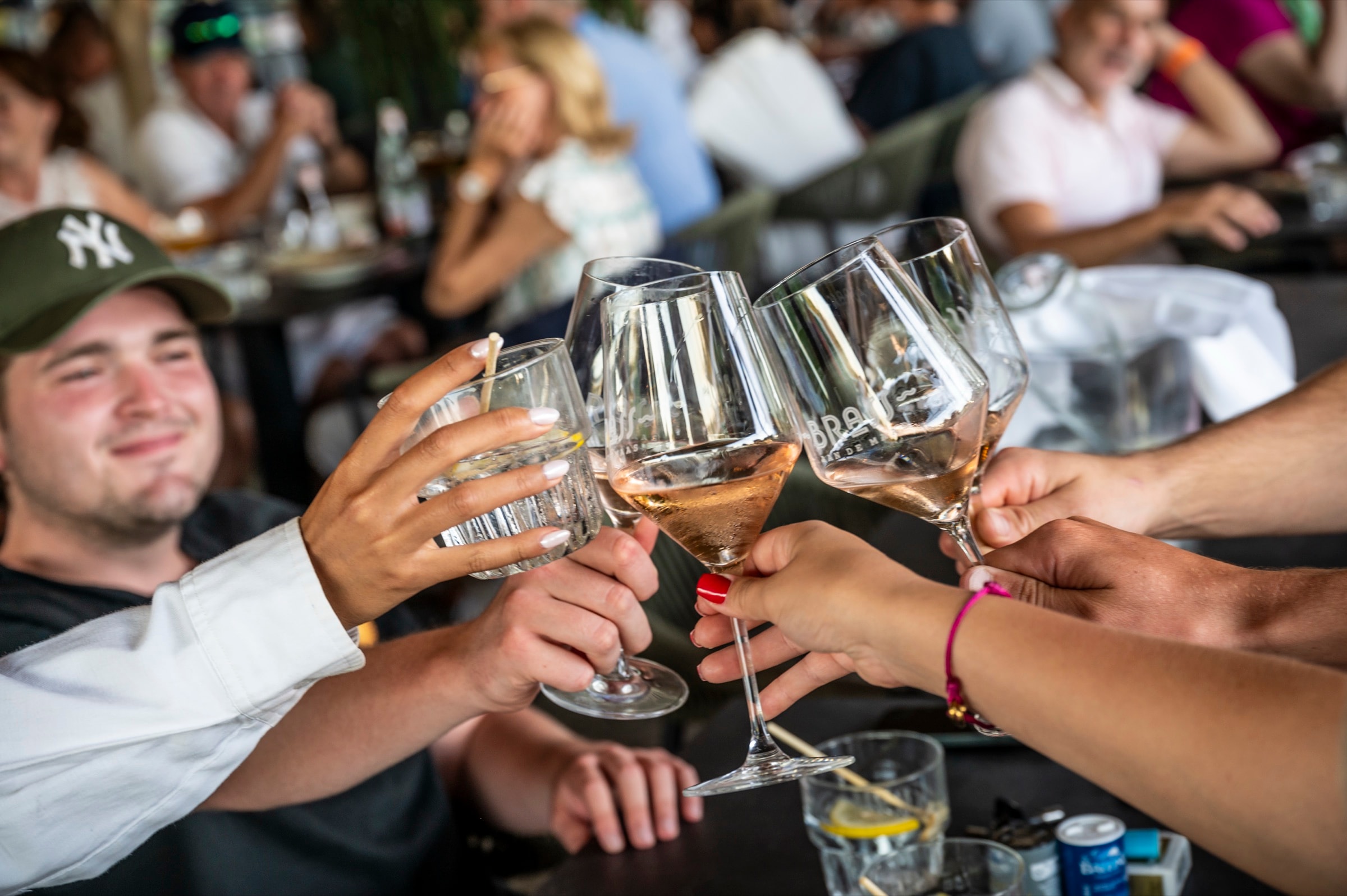 Vier mensen proosten met wijnglazen aan een tafel op een terras.